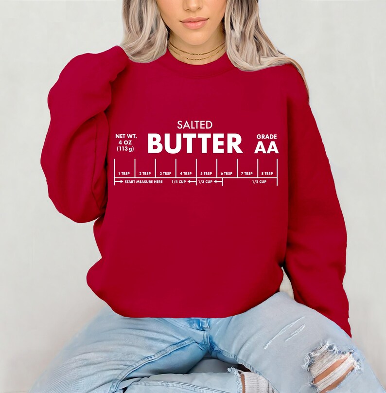 May include: A deep red sweatshirt with white text that reads "SALTED BUTTER AA" and a butter measurement guide. The net weight is 4 oz (113g). The measurement guide includes increments from 1 tbsp to 1/2 cup.