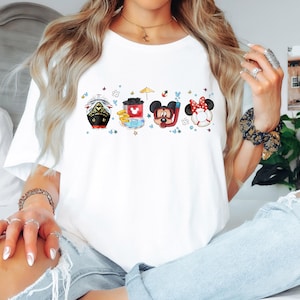 May include: White t-shirt featuring a colourful graphic of Mickey Mouse and Minnie Mouse characters in a boat, a red cup, and a life preserver. The characters are surrounded by stars and other nautical elements.
