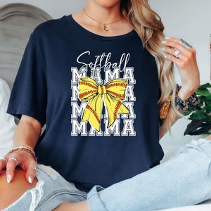 K&ouml;nnte beinhalten: Marineblaues T-Shirt mit einer gelben Softball-Schleife und dem Text "Softball Mama", der viermal wiederholt wird.