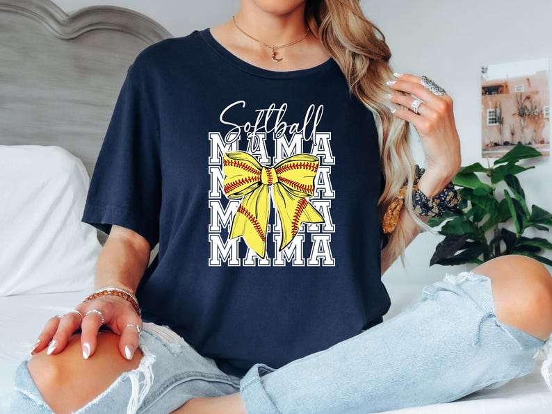 K&ouml;nnte beinhalten: Marineblaues T-Shirt mit einer gelben Softball-Schleife und dem Text "Softball Mama", der viermal wiederholt wird.
