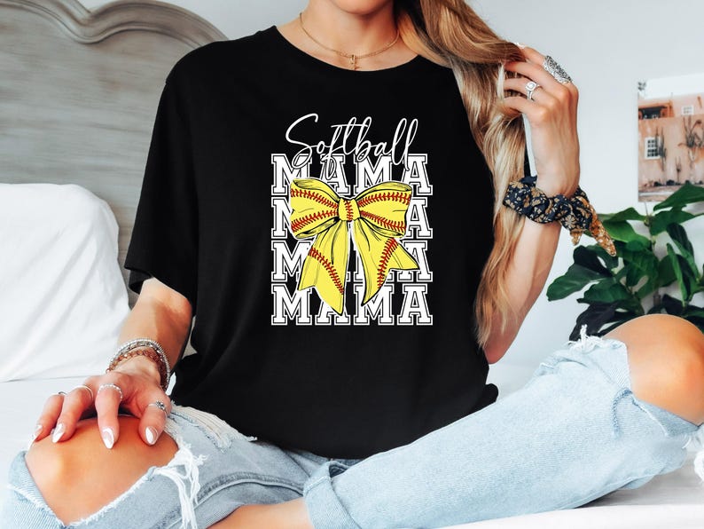 K&ouml;nnte beinhalten: Schwarzes T-Shirt mit einer gelben und roten Softball-Schleife und dem Text "Softball Mama" wiederholt in Wei&szlig;.