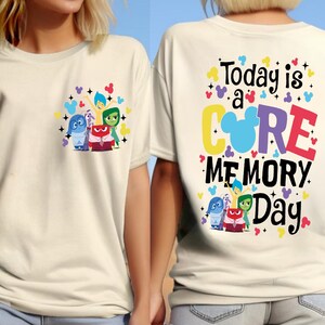May include: Two white t-shirts with a graphic design featuring characters from the movie Inside Out. The front shirt has the characters Joy, Sadness, Anger, Disgust, and Fear. The back shirt has the text "Today is a CORE MEMORY Day" with a Mickey Mouse head inside the word "CORE".
