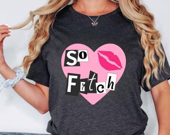 May include: A dark grey t-shirt with a pink heart graphic. The heart has the words "SO FETCH" in black letters and a pink lipstick print.