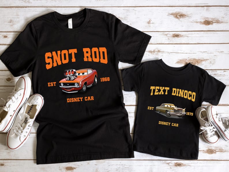 May include: Two black t-shirts with a Cars movie theme. The larger shirt features an orange car with the text "Snot Rod Est 1968 Disney Car". The smaller shirt features a gold car with the text "Text Dinoco Est 1975 Disney Car".