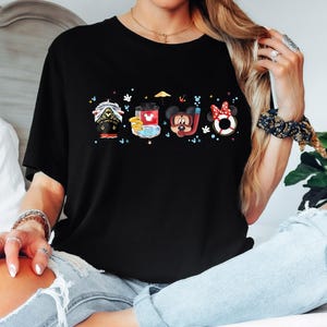 May include: Black t-shirt featuring a colourful graphic of Mickey Mouse and his friends on a boat, a beach umbrella, and a life preserver. The graphic includes the text "Mickey Mouse" and "Disney".