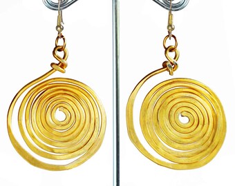 May include: A pair of gold-toned spiral earrings. The earrings are made of a thick, coiled wire that forms a circle. The earrings are hanging from a silver earring stand.