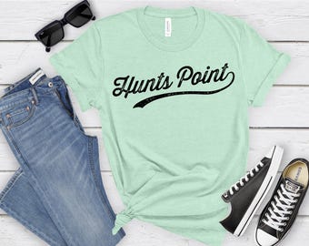 May include: A light green t-shirt with a black vintage-style graphic that says "Hunts Point".