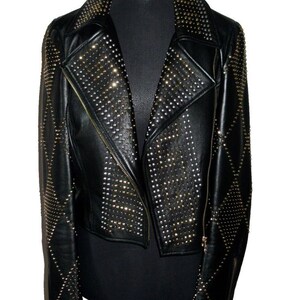 May include: A black leather jacket with a diamond pattern and gold studs. The jacket has a zip closure and a collar.