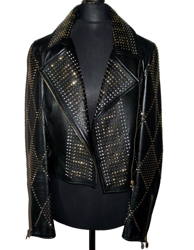 May include: A black leather jacket with a diamond pattern and gold studs. The jacket has a zip closure and a collar.