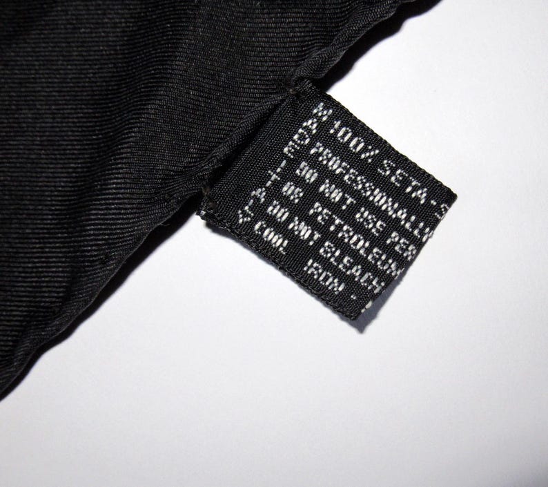 Puede incluir: Etiqueta de tela negra con texto blanco que dice "100% SETA - S", "PROFESSIONALLY", "30 NOT USE PER", "T08 PETROLEUM", "DO NOT BLEACH", "COOL", "IRON!"