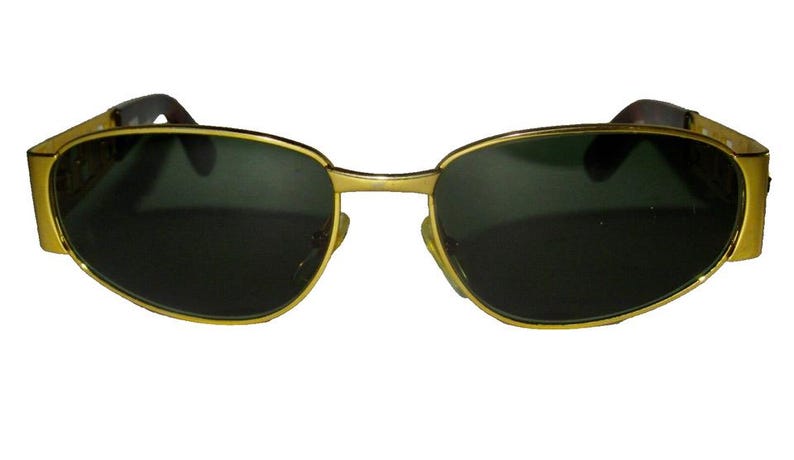 May include: Gold-tone sunglasses with dark lenses. The sunglasses have a rectangular shape and a thin metal frame.