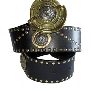 Peut inclure: Une ceinture en cuir noir avec des clous dorés et une grande boucle dorée ornée d'un motif de tête de lion argenté.
