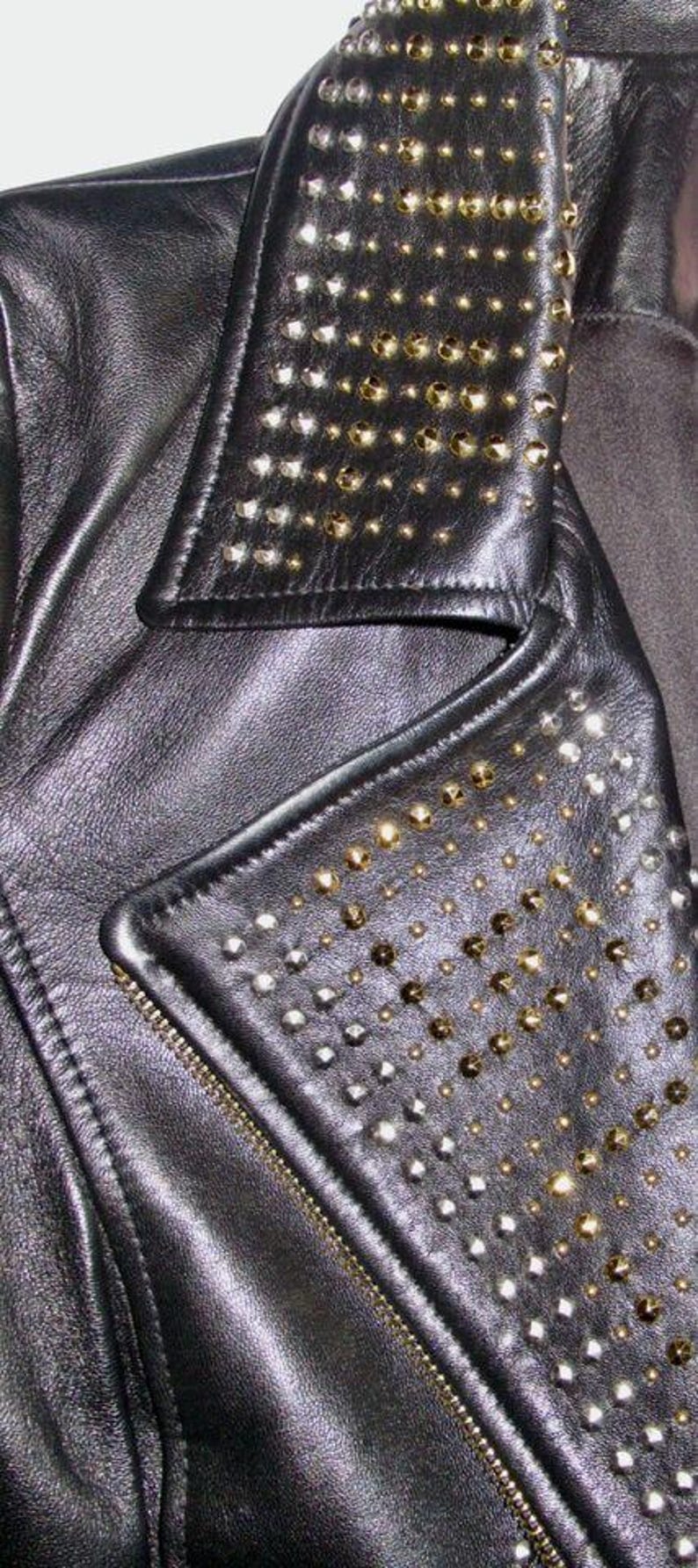 May include: Black leather jacket with a studded collar and a zip closure. The collar and the front flap are decorated with silver and gold studs.