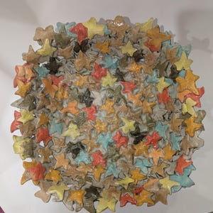 May include: A ceramic bowl with a unique design featuring a multitude of small, leaf-shaped forms in various shades of yellow, orange, red, blue, and green.