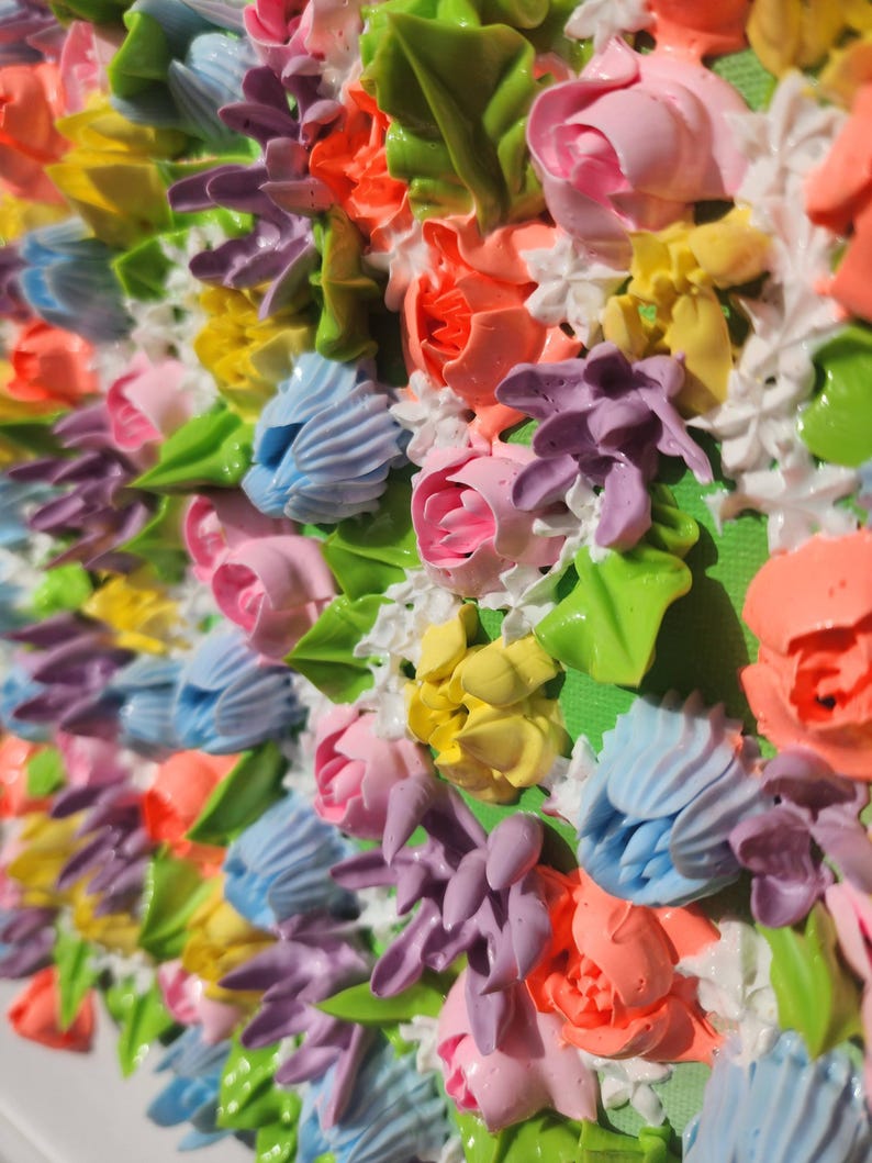 May include: A textured painting featuring a dense arrangement of three-dimensional floral shapes in vibrant shades of pink, orange, yellow, light blue, and purple, accented with small white blossoms and green leaves on a bright green background.