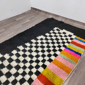 May include: A black and white checkered rug with a colorful striped border. The stripes are red, orange, yellow, green, blue, and pink.
