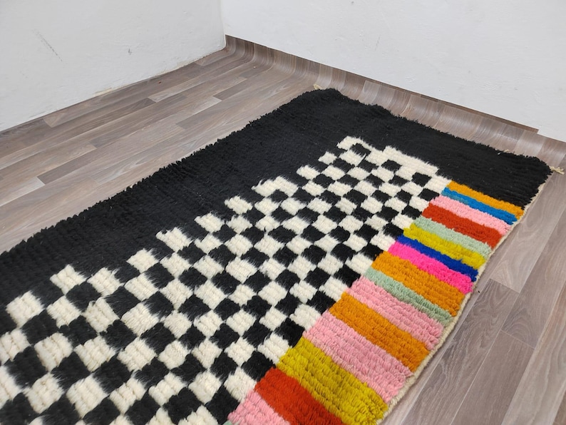 May include: A black and white checkered rug with a colorful striped border. The stripes are red, orange, yellow, green, blue, and pink.