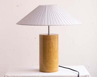 Handmade ceramic table lamp, a lighting and decorative object. Bright yellow base and light gray ribbon shade.