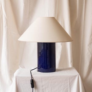 Handcrafted ceramic table lamp, a decorative and lighting object. Glossy blue ceramic base and white canvas shade.