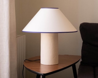 Handmade ceramic table lamp, a lighting and decorative object. Beige ceramic base and shade with purple trim.