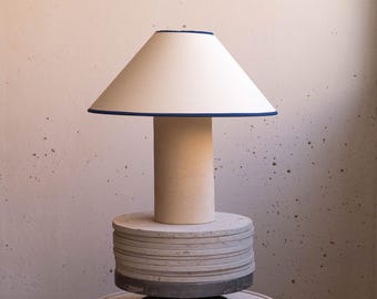 Handmade ceramic table lamp, a lighting and decorative object. Beige ceramic base and shade with blue trim.