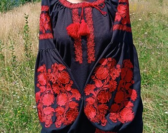May include: A black embroidered blouse with red floral designs and a matching red and white striped skirt. The blouse has a round neckline and long sleeves. The skirt has a wide waistband and a flowing silhouette.
