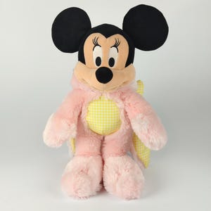 May include: A plush Minnie Mouse doll wearing a pink and yellow butterfly costume. The doll has black ears, a black nose, and a pink and yellow gingham pattern on the chest. The doll is approximately 12 inches tall.