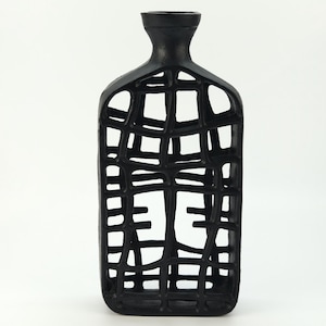 May include: A black, rectangular vase with a lattice design. The vase has a narrow neck and a wide, open body. The lattice pattern creates a cage-like effect, with the negative space forming geometric shapes. The vase is made of a solid material and has a matte finish.