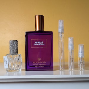 May include: A set of five perfume bottles, including a large bottle with a purple label that reads "Vanille Patchouli" and the brand name "Molinard." The smaller bottles are labeled with their volume in milliliters: 12ml, 10ml, 5ml, and 3ml.