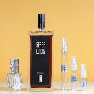 May include: A set of four perfume bottles. The largest bottle is a clear glass bottle with a black cap and a red liquid. The bottle has the text "Serge Lutens Chergui" on the label. The other three bottles are smaller and clear with white caps. The bottles are labeled with the text "10ml sample", "5ml sample", and "3ml sample".