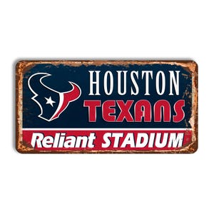 Puede incluir: Un letrero de metal de estilo vintage con un acabado oxidado. El letrero presenta el logotipo de los Houston Texans, el nombre del equipo "HOUSTON TEXANS" y las palabras "Reliant STADIUM". El letrero es de color azul, rojo y blanco.