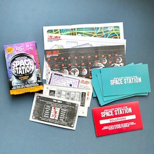Peut inclure: Un jeu de puzzle "Escape from the Space Station" en boîte avec divers composants. La boîte est violette, rose et blanche, avec un astronaute. Comprend des cartes, une carte et une carte de solution. Le jeu est pour les 12 ans et plus.