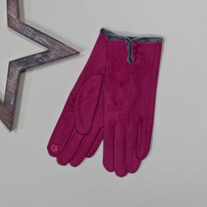 May include: A pair of pink gloves with a gray faux fur trim. The gloves have a button detail on the back of the hand.