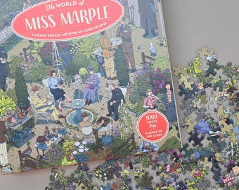May include: A jigsaw puzzle box with the title "The World of Miss Marple" and a colorful illustration of a garden scene with people. The puzzle contains 1000 pieces and a guide to the clues.