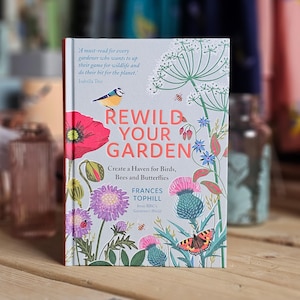 May include: A hardcover book titled "Rewild Your Garden" with floral and insect illustrations. The cover features a blue tit, poppies, bees, and butterflies. The book's subtitle is "Create a Haven for Birds, Bees and Butterflies."