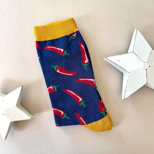 May include: A pair of blue socks with a yellow cuff and a red chilli pepper pattern.