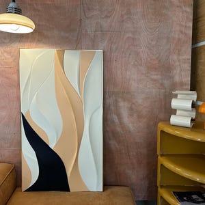 Pu&ograve; includere: Arte da parete astratto con un design bianco, beige e nero. L'arte &egrave; incorniciata e ha uno stile moderno e minimalista.