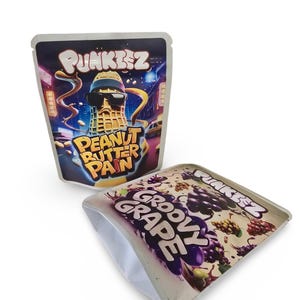 May include: Two colourful pouches with the brand name "PUNKIEZ" printed on them. One pouch features a cartoon peanut wearing sunglasses and the text "PEANUT BUTTER PAIN". The other pouch features a purple and white design with the text "GROOVY GRAPE".