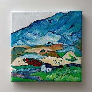 May include: An original landscape painting on canvas. The artwork depicts rolling hills, a small white house, and a large blue mountain range. The colour palette includes shades of blue, green, brown, and red, creating a vibrant and expressive scene.