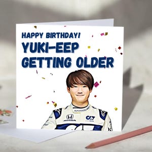 Può includere: Un biglietto di auguri bianco con la scritta "HAPPY BIRTHDAY! YUKI-EEP GETTING OLDER" in blu. Il biglietto presenta un'illustrazione di una persona in uniforme da corsa e coriandoli. Una matita rosa è in primo piano.
