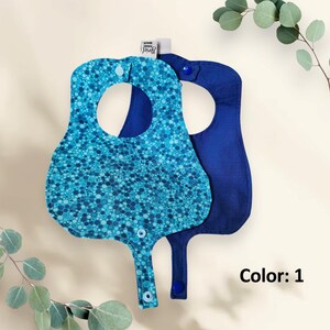 May include: Two baby bibs, one blue with a blue and turquoise polka dot pattern and one solid blue. Both bibs have a snap closure and a neck opening. The text "Color: 1" is visible in the image.