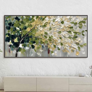 May include: A framed abstract painting of a tree with textured brushstrokes. The artwork features a tree trunk and branches with green, yellow, and white leaves against a gray background. The painting is displayed above a light-colored cabinet.