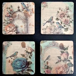 May include: Set of four square coasters featuring a vintage floral design with blue birds and a birdcage. The coasters have a distressed, antique look and are perfect for adding a touch of elegance to any home.