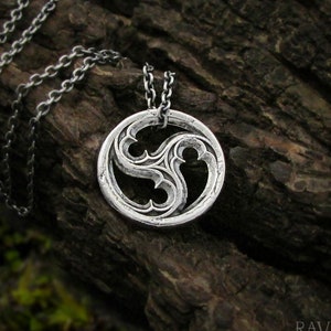 May include: A silver necklace with a circular pendant featuring a stylised, three-leaf design. The pendant has a textured, hammered finish.