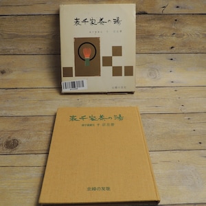 May include: Two hardcover books with beige and tan covers featuring Japanese calligraphy and a graphic illustration of a tea whisk. The top book includes a barcode sticker on the lower left corner and brown square accents on the front cover.
