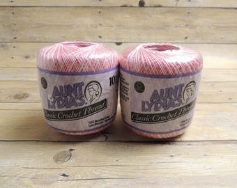 May include: Two balls of Aunt Lydia's Classic Crochet Thread in a variegated pink and white colorway. Each ball is wrapped in clear plastic packaging featuring the brand name, a profile illustration, and the text 100% Mercerized Cotton.
