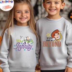 May include: Two children wearing light gray sweatshirts. One sweatshirt features Buzz Lightyear with the text "To Infinity" and stars. The other sweatshirt has Woody with the text "And Beyond" and a star. Both sweatshirts are long-sleeved.