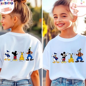 Könnte beinhalten: Weiße T-Shirts mit einem Cartoon-Design von Disney-Figuren: Donald Duck, Mickey Mouse, Pluto und Goofy. Die Figuren sind in einer Reihe angeordnet. Die T-Shirts werden von einer jungen Person getragen.