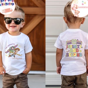 Puede incluir: Camiseta blanca con un gr&aacute;fico colorido de Buzz Lightyear y Woody con el texto "To Infinity and Beyond". La parte posterior de la camiseta tiene la misma frase con un dise&ntilde;o de cohete y estrella. La camiseta la lleva un ni&ntilde;o peque&ntilde;o.