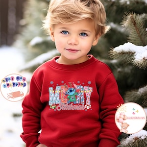 Puede incluir: Una sudadera roja para ni&ntilde;os con la palabra "MERRY" en un dise&ntilde;o floral, y el personaje Stitch de Lilo & Stitch. La palabra "Stitchmas" est&aacute; debajo. El ni&ntilde;o lleva la sudadera en un entorno nevado al aire libre.